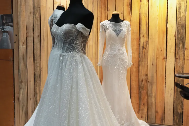 Vestidos de novia expuestos junto a una pared de madera
