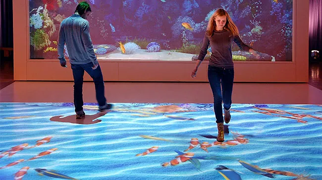 Personas caminando sobre una proyección interactiva de peces