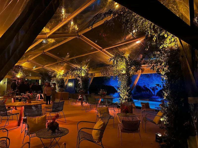 Carpa con iluminación cálida y vegetación exterior iluminada en azul