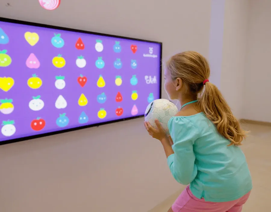 Niña interactuando a distancia con una pantalla de gran formato